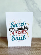 Load image into Gallery viewer, A white greeting card sitting on a a wood table top with the words &quot;A Sweet Friendship Refreshes the Soul.&quot;