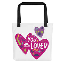 Load image into Gallery viewer, A white tote bag with black handles on a white background. The bag features a design with the words &#39;you are loved&#39; inside two illustrated pink hearts with a smaller, purple heart above. 