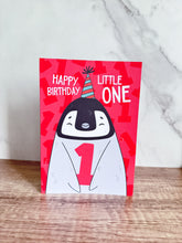 Load image into Gallery viewer, A greeting card standing up on a table. The card features an illustrated penguin with a party hat on and holding the number one and reads &quot;Happy birthday little one.&quot;