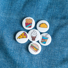 Load image into Gallery viewer, A set of six button pins on a jean jacket. The pins feature illustrations of a taco, pizza slice, french fries, an ice cream cone, a milkshake and a burger. 