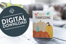 Load image into Gallery viewer, A greeting card featured on a black, wood coffee table. There’s a white planter in the background with a green plant. There’s also a gray sofa in the background with a white pillow. The card features the words &quot;Happy Thanksgiving” with illustrated pumpkins. The words &quot;digital download&quot; are featured in a circle over the image