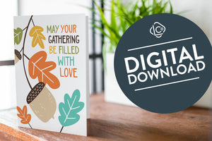 A greeting card is featured on a wood coffee table with a green plant in a white planter in the background. The card features the words “May Your Gathering Be Filled with Love” with illustrated leaves and an acorn around the words. The words "digital download" are featured in a circle on top of the image.