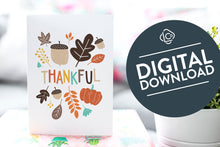 Load image into Gallery viewer, A greeting card is featured on pink wrapped gift with a green plant in the background. The card features illustrated lettering reading “Thankful&quot; with illustrated leaves and an acorn around the word. The words &quot;digital download&quot; are featured in a circle over the image.