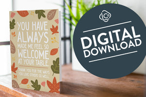 A photo of a card featured on a tabletop next to a white planter filled with a green plant. ​​The card features the words "You have always made me feel so welcome at your table. Thank you for the ways You love others so well" with illustrated leaves surrounding the words. The words "digital download" are featured in a circle over the image.