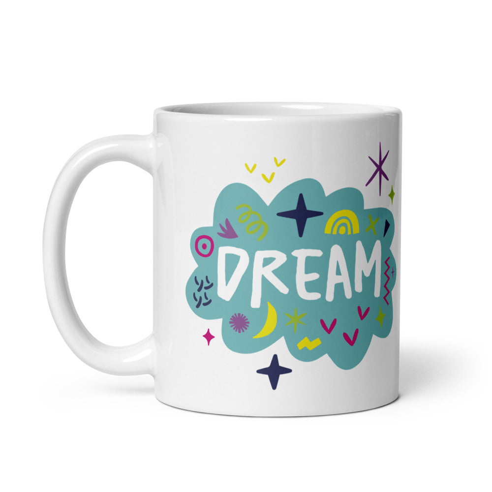 A white ceramic mug on a white background. The mug features a design with the word 'dream' in an illustrated cloud with sketchy elements around it. 