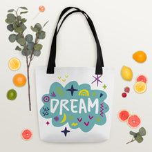 Load image into Gallery viewer, A white tote bag with black handles on a white background with oranges and eucalyptus leaves around. The bag features a design with the word &#39;dream&#39; with an illustrated cloud around the word with colorful sketchy around. 