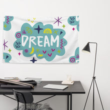 Load image into Gallery viewer, A large flag is featured hanging on the wall of an office placed above a desk. The white flag features a pattern with the word &quot;dream&quot; featured inside a cloud with sketchy illustrations around the word. 