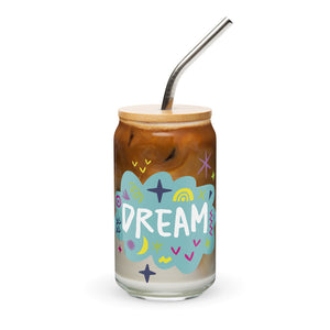 A photo of a glass can tumbler on a white background with a bamboo lid and silver metal straw. The design on the glass tumbler says the word "dream" inside a teal cloud illustration with sketchy illustrations around. 