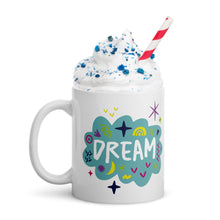 Load image into Gallery viewer, A white mug on a white background with whipped cream and a straw. The mug features a design with the word &#39;dream&#39; in an illustrated cloud with sketchy elements around it. 