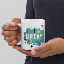 Load image into Gallery viewer, A person holding a white mug. The mug features a design with the word &#39;dream&#39; in an illustrated cloud with sketchy elements around it. 