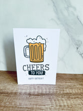 Load image into Gallery viewer, A greeting card sitting upright on a table top. The card features the words “Cheers to you, happy birthday” with an illustrated beer mug.