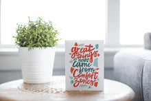 Load image into Gallery viewer, A greeting card laying on a wooden table with some cut wood details. The card features the words “Great things never came from comfort zones.”