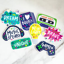 Load image into Gallery viewer, A pack of 8 vinyl, die-cut stickers featuring the words brave, unique, music speaks, good vibes, be the light, I love books.