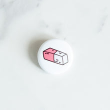 Load image into Gallery viewer, A button pin on a white tabletop. The button features an illustration of an eraser. 