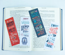 Load image into Gallery viewer, A set of four bookmarks laying across an open Bible. The Bible is on a white tabletop. 
