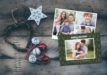 Load image into Gallery viewer, A photo of a Christmas card showing the front and back of the card laying on a wood surface. To the left of the cards are some ornaments. The front of the card features a photo with a frame around it with illustrated pine trees. Above the photo reads “Merry Christmas” and below the photo you can add your family name. The back of the card features three photos with illustrated pine trees. 
