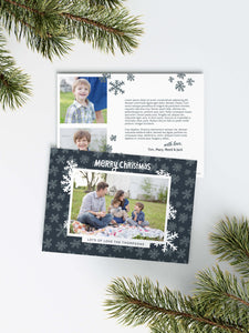 A photo of a Christmas card showing the front and back of the card laying on a white surface. Around the two sides of the card are pine needles. The front of the card features a photo with a frame around it with illustrated snowflakes. Above the photo reads “Merry Christmas” and below the photo you can add your family name. The back of the card features two photos, illustrated snowflakes and a place to add a family update. 