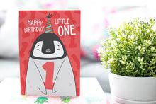 Load image into Gallery viewer, A greeting card standing up on a wrapped gift with a plant next to it. The card features an illustrated penguin with a party hat on and holding the number one and reads &quot;Happy birthday little one.&quot;