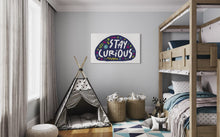 Load image into Gallery viewer, A large flag featured on a wall of a kids room. The white flag features the words &quot;stay curious&quot; featured inside a a purple shape with sketchy illustrations around. 