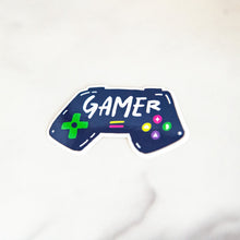 Load image into Gallery viewer, A vinyl die cut sticker with the word &quot;gamer&quot; inside an illustrated game contoller.