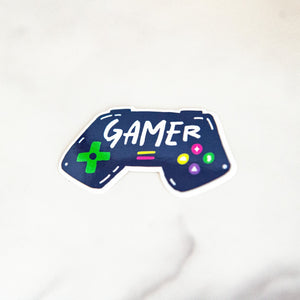 A vinyl die cut sticker with the word "gamer" inside an illustrated game contoller.