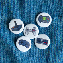 Load image into Gallery viewer, A set of five button pins on a jean jacket. The buttons feature five different illustrations of game controllers. 