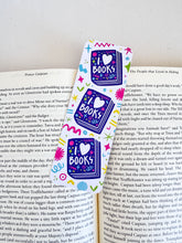 Load image into Gallery viewer, A bookmark placed inside a book. The bookmark features the words &quot;i love books&quot; with love shown shaped as a heart. The words are placed inside an illustrated book. 