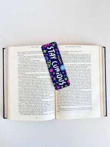 A bookmark placed inside a book. The bookmark has the words "stay curious" with fun, sketchy illustrations. 