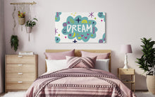 Load image into Gallery viewer, A large flag featured on the wall of a teen girls&#39; room above the bed. The white flag features a pattern with the word &quot;dream&quot; featured inside a cloud with sketchy illustrations around the word. 