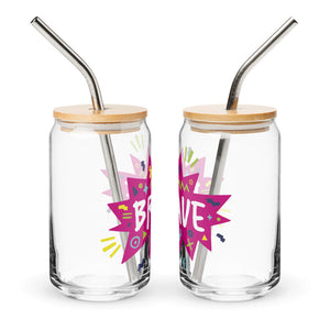 A photo of two glass can tumblers on a white background showing the side of the glasses. The glass tumblers have a bamboo lid and silver metal straw. The design on the glass tumbler says the word "brave" inside a hot pink star with illustrated sketchy elements around the word. 