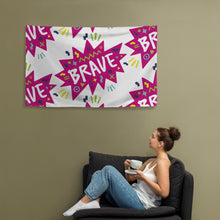 Load image into Gallery viewer, A large flag is featured hanging on the wall with a woman sitting on a sofa below it. The white flag features a pattern with the word &quot;brave&quot; featured inside a pink star-like shape with sketchy illustrations around the word. 