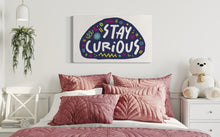 Load image into Gallery viewer, A large flag featured on a wall of a girls bedroom above the bed. The white flag features the words &quot;stay curious&quot; featured inside a a purple shape with sketchy illustrations around. 