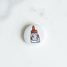 Load image into Gallery viewer, A button pin on a white tabletop. The button features an illustration of a glue bottle. 