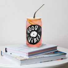 Load image into Gallery viewer, A photo of a glass can tumbler on a coffee table on top of books. The glass tumbler has a bamboo lid and silver metal straw. The glass tumblers have a bamboo lid and silver metal straw. The design on the glass tumbler says the words &quot;good vibes&quot; inside an illustrated vinyl record.