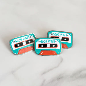 Three enamel pins featuring the words "good vibes" inside an illustrated cassette tape.