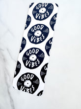 Load image into Gallery viewer, A bookmark on a tabletop. The bookmark features the words &quot;good vibes&quot; inside an illustrated vinyl record.