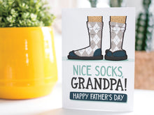 Load image into Gallery viewer, A greeting card is on a table top with a yellow plant pot and a green plant inside. The card features the words “Nice Socks Grandpa, Happy Father’s Day” with an illustrated of legs with patterned socks and shoes. 