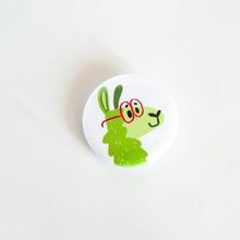 Load image into Gallery viewer, A buttons on a white tabletop. The button features a green illustrated llama with red glasses on. 