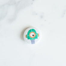 Load image into Gallery viewer, A button pin on a white tabletop. The button features an illustration of a green robot.