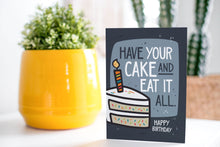 Load image into Gallery viewer, A greeting card is on a table top with a yellow plant pot and a green plant inside. The card features the words “Have Your Cake and Eat it All Happy Birthday” with an illustrated piece of cake with a candle in it.