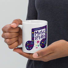 Load image into Gallery viewer, A person holding a white mug. The mug features a design with the words &#39;music speaks&#39; in an illustrated musical note with sketchy elements around it.