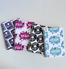 Load image into Gallery viewer, A set of four spiral bound notebooks. The notebooks feature a pattern design  with the words brave, dream, good vibes and I love books. 