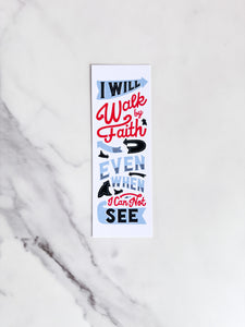 A bookmark laying on a marble tabletop with a white background and the words "I will walk by faith even when I can not see."