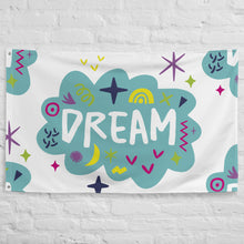 Load image into Gallery viewer, A large flag featured on a white brick wall. The white flag features a pattern with the word &quot;dream&quot; featured inside a cloud with sketchy illustrations around the word. 