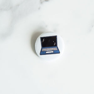 A buttons on a white tabletop. The button features an illustration of a laptop.