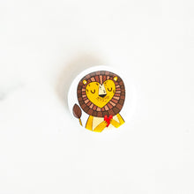 Load image into Gallery viewer, A button pin on a white tabletop. The button design features an illustrated lion. 