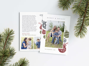 A photo of a Christmas card showing the front and back of the card laying on a white surface. Around the two sides of the card are pine needles. The front of the card features a photo with the words Merry & Bright at the top and illustrated ornaments around the photo. The back of the card features two photos, illustrated ornaments and space to write a family update.