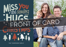 Load image into Gallery viewer, A close up of the front of the card showing the front of the card design. Across the image is a gray strip with the words “front of card” on it. The front of the card features a photo on the right side and on the left side are the words “ Miss you and sending hugs to you this Christmas” with illustrated trees below the words. 