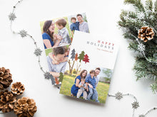 Load image into Gallery viewer, A photo of a double-sided Christmas card showing the front and back of the card laying on a white surface. Around the two sides of the card are pine cones, pine needles and a string of silver snowflake garland. The front of the card features a photo on the bottom and on the top it reads “Happy Holidays, The Franklins” with illustrated modern pine trees. The back of the card features three photos. 
