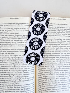 A bookmarks placed inside a book. The bookmark features the words "good vibes" inside an illustrated vinyl record.